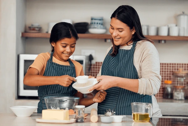 Child learning basic life skills by helping in the kitchen at home